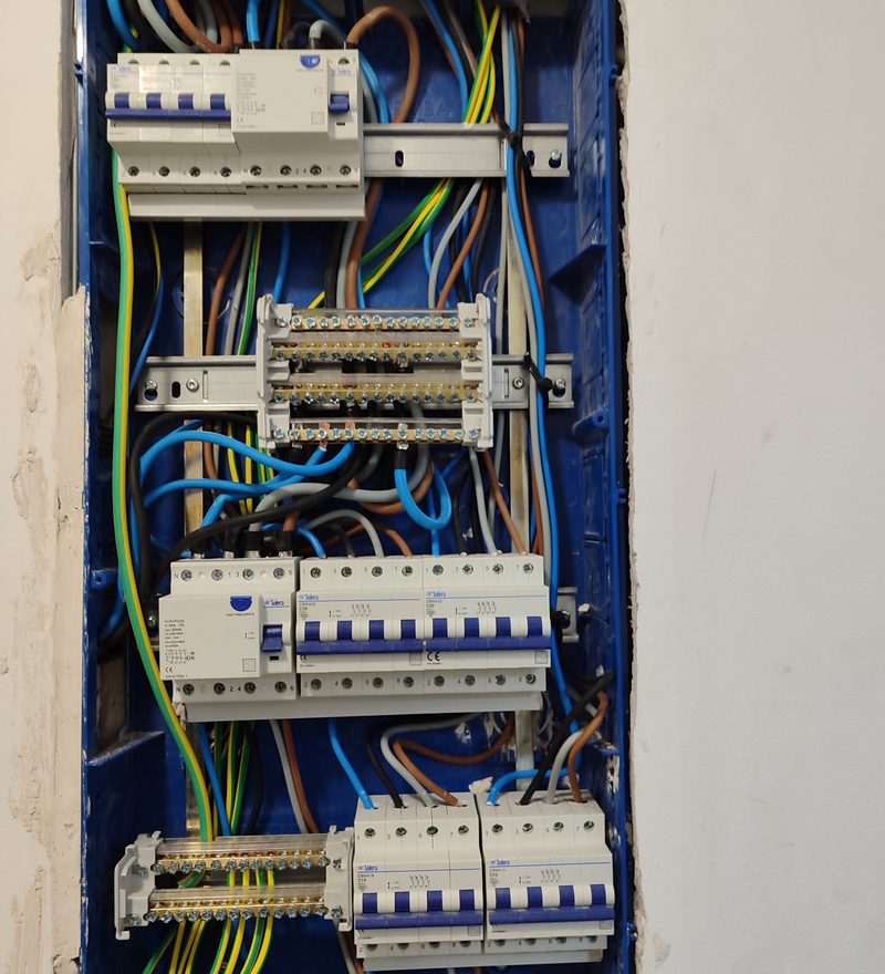 Cuadro eléctrico de vivienda empotrado en pared de ladrillo visto, con el cableado ordenado